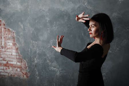 Young adult spanish woman dancing flamenco on gray vintage studio backgroundの写真素材