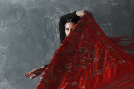 Young adult spanish woman dancing flamenco on gray vintage studio backgroundの写真素材