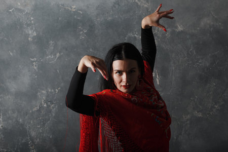 Young adult spanish woman dancing flamenco on gray vintage studio backgroundの写真素材