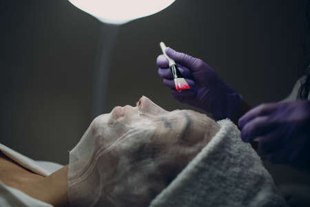 Paraffin Face Mask gauze bandage Therapy Young Woman Receiving Facial Skin Care Treatment. Beautician Pouring Wax Applying.の写真素材