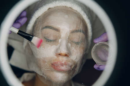 Paraffin Face Mask gauze bandage Therapy Young Woman Receiving Facial Skin Care Treatment. Beautician Pouring Wax Applying.の写真素材