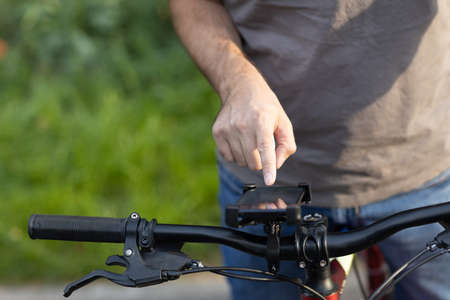 Man planning route using GPS navigation application in mobile phone on his bicycle bikeの写真素材