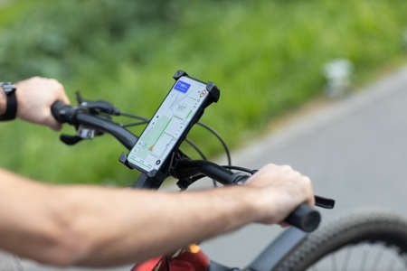Man planning route using GPS navigation application in mobile phone on his bicycle bikeの写真素材