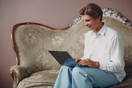 Portrait european young man sitting with laptop at studioの写真素材