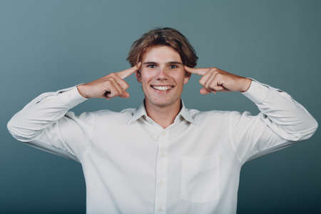 Portrait european young positive thinking man portrait with hand fingers at headの写真素材