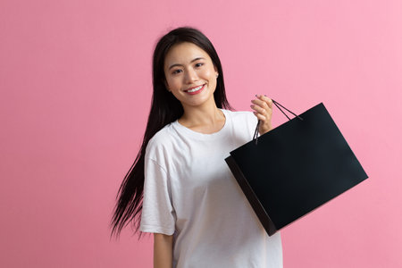 Shopping asian happy woman holding shopping bags on pink background and smilesの写真素材