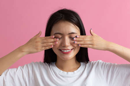 Close up face portrait of young asian woman doing facebuilding yoga face skin and eyes gymnastics yoga massage.の写真素材