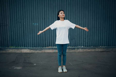 Asian young woman doing qigong exercise summer outdoor spreads armsの写真素材