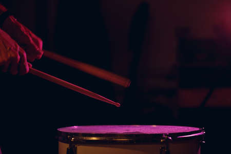 Close up drum sticks drumming hit beat rhythm on drum surface with splash water drops with long...