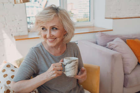 Elderly caucasian old aged woman enjoying afternoon tea at homeの写真素材