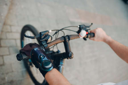 Young disabled man with artificial prosthetic hand in casual clothes riding bicycleの写真素材
