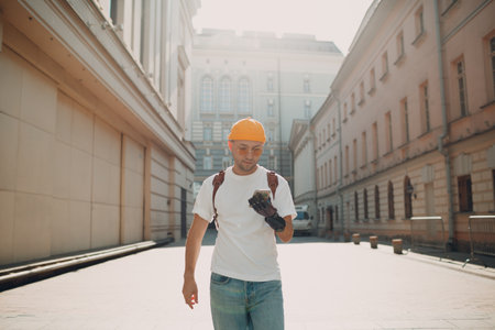 Young disabled man tourist using mobile phone with artificial prosthetic hand and walking at sunny city street outdoorの写真素材