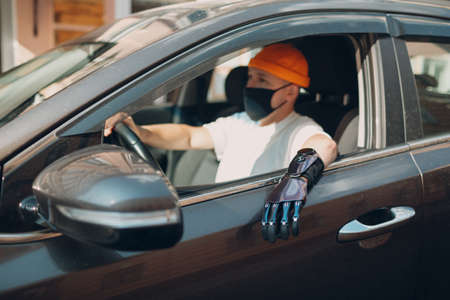 Young disabled man driver with artificial prosthetic hand driving vehicle carの写真素材