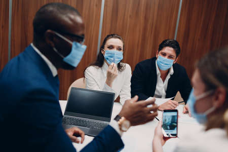 Colleagues diverse team wearing face mask office meeting. Business people men and women group...