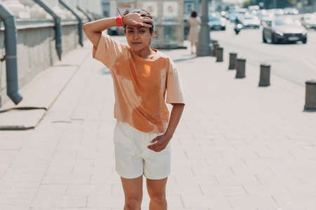 Young indian woman runner jogging in wet sweaty t-shirt at city street.の写真素材