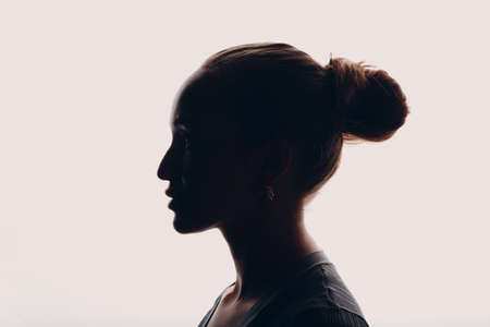 Adult young woman dark silhouette portrait in studioの写真素材