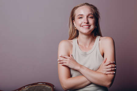Portrait of young smiling european woman. Beautiful happy blonde girl wears t-shirt and looks at camera. Studio shoot isolated on pink background.の写真素材