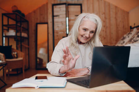 Mature Woman with laptop sitting at table and talking in glamping camping tent. Modern vacation lifestyle conceptの写真素材
