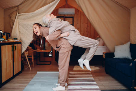 Family doing exercises sports indoors. Young and senior elderly woman relaxing at glamping camping tent. Mother and daughter modern vacation lifestyle conceptの写真素材