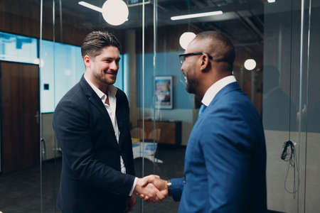 Businessman handshake success deal team at office meeting. Business people group conference discussion sit at table with boss man shaking hands and smilesの写真素材