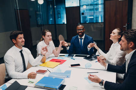 Businessman and businesswoman team meditate and holds hands each other after office meeting. Business people group conference discussion meditation conceptの写真素材