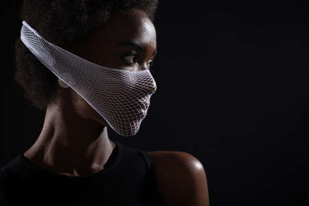 Portrait of african american dark skin woman fashion model wearing quarantine medical fishnet knitting face mask coarse mesh net. Covid-19 coronavirus protection unsafe dangerous concept.の写真素材