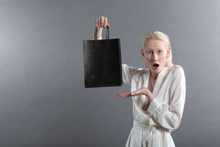 White caucasian albino blond woman holds shopping bag. Sale and discounts on market and Black Friday concept.の写真素材