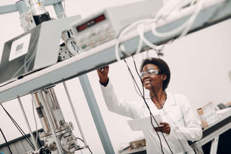 Scientist african american woman working in laboratory with electronic tech single photon detector. Research and development of electronic devices by color black woman.の写真素材