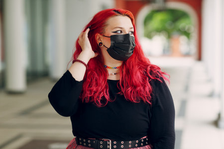 European plus size woman portrait in face mask outdoor street city. Young red pink haired body positive girl.の写真素材