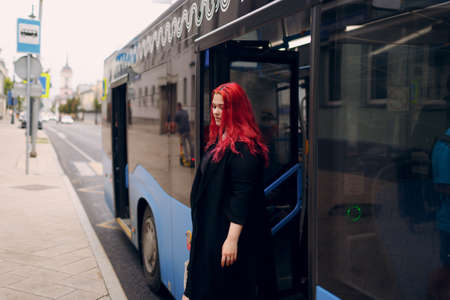 European plus size woman comes out of bus. Young red pink haired body positive girl.の写真素材