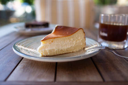 Cheescake San Sebastian slice on dish at cafe table.の写真素材