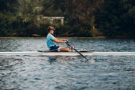 Sportsman single scull man rower rowing technique on boat. Paddle oar splash movement motionの写真素材