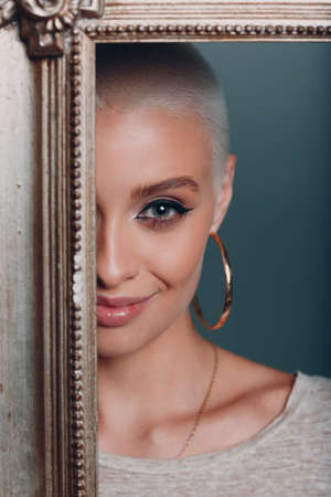 Millenial young woman with short blonde hair gilded picture frame face portraitの写真素材