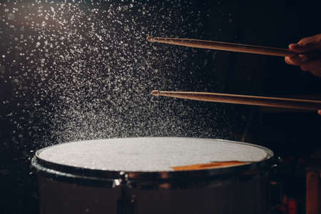 Close up drum sticks drumming hit beat rhythm on drum surface with splash water flying dropsの写真素材