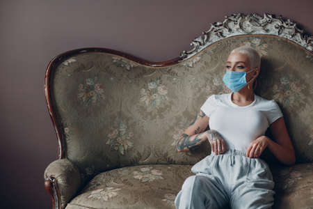 Millenial young woman with face mask short blonde hair portrait sitting face coveringの写真素材