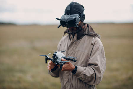 Man controlling fpv quadcopter drone for aerial photography and videography with goggles antenna remote controller.の写真素材