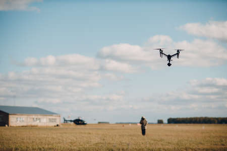 Big quadcopter drone on aerial flight and filming man and helicopter.の写真素材