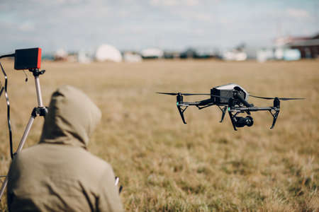 Man pilot controlling quadcopter drone with remote controller screen displayの写真素材