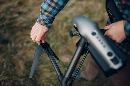 Man pilot checking quadcopter drone propeller blades before aerial flight and filmingの写真素材