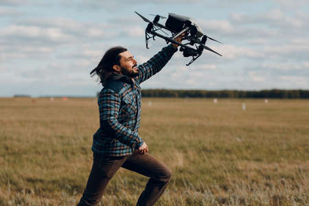 Man pilot holding quadcopter drone in handand running at outdoor fieldの写真素材