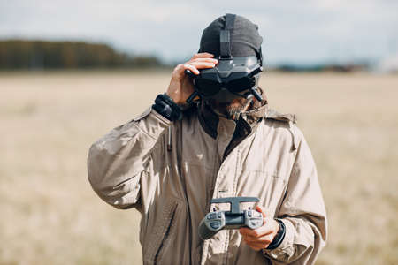 Man controlling fpv quadcopter drone for aerial photography and videography with goggles antenna remote controller.の写真素材