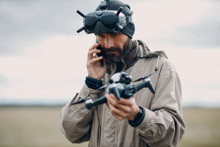 Man controlling fpv quadcopter drone for aerial photography and videography with goggles antenna remote controller.の写真素材