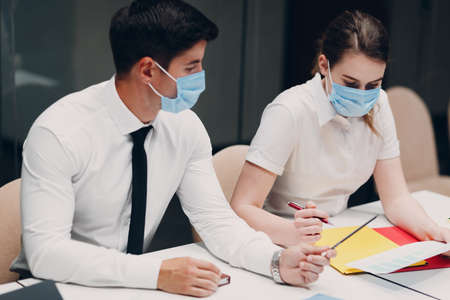 Businessman and businesswoman team in medical face mask at office meeting. Business people group conference discussion with boss.の写真素材