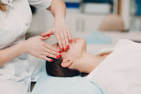 Beautiful young woman getting face treatment massage at beauty spaの写真素材