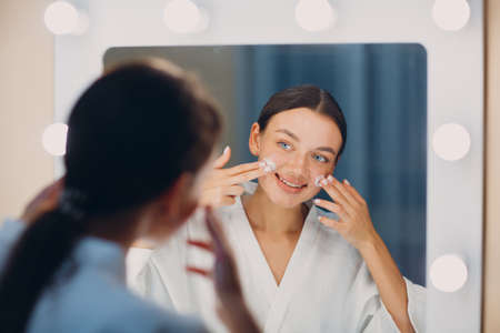 Young woman applying cosmetic white cream on faceの写真素材