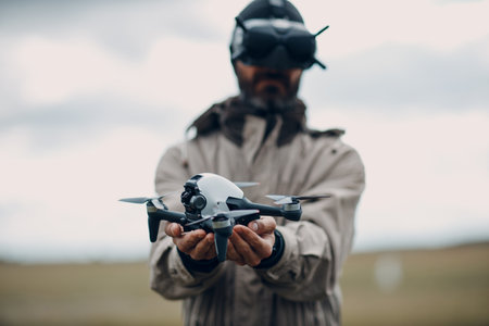 Man controlling fpv quadcopter drone for aerial photography and videography with headset antenna remote controller.の写真素材
