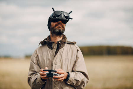 Man controlling fpv quadcopter drone for aerial photography and videography with headset antenna remote controller.の写真素材