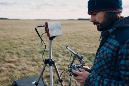Man pilot controlling quadcopter drone with remote controller pad.の写真素材
