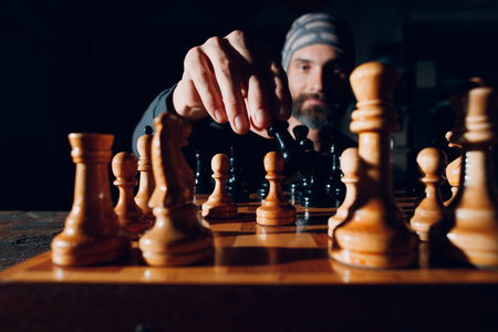 Young adult handsome man playing chess in dark with side lit.の写真素材