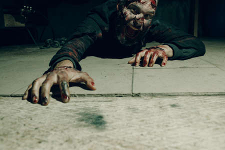 Zombie male creeps on floor halloween concept. Make up skin and blood faceの写真素材